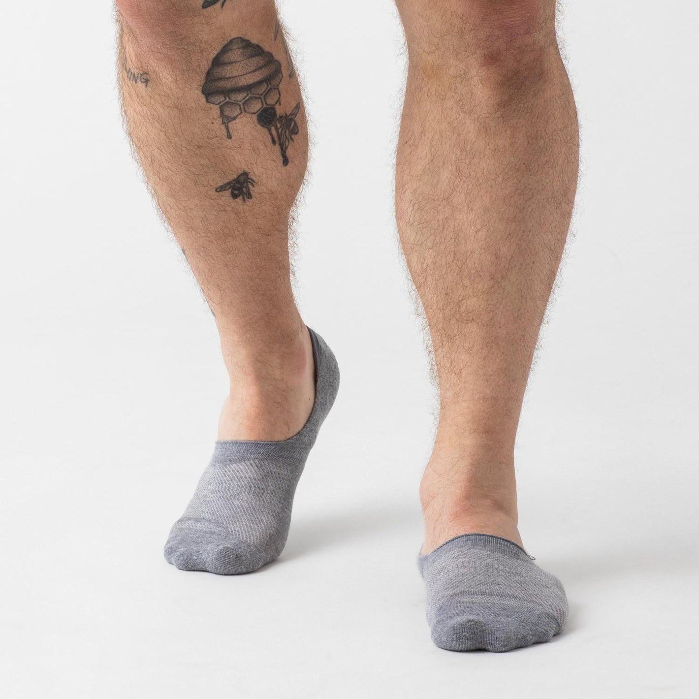 3 Day Travel Pack: Person wearing light gray no-show socks with tattoos.