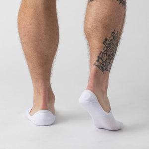 True ClassicWhite Never Show Socks 6-Pack on tattooed legs, showcasing low-cut design.