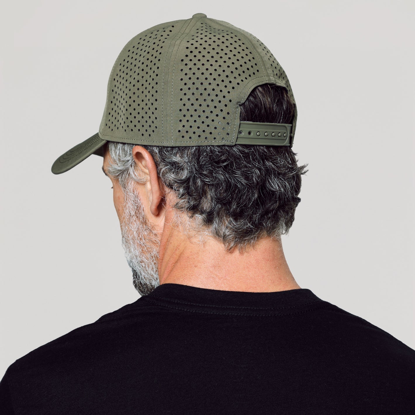 Man wearing Military Green All Purpose Cap, perforated with snapback closure.