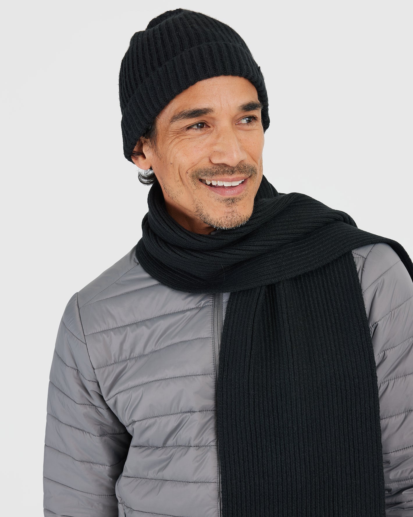 Man wearing Black Sweater Scarf and gray quilted jacket.