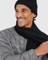 Man smiling in Black Sweater Scarf and quilted jacket.