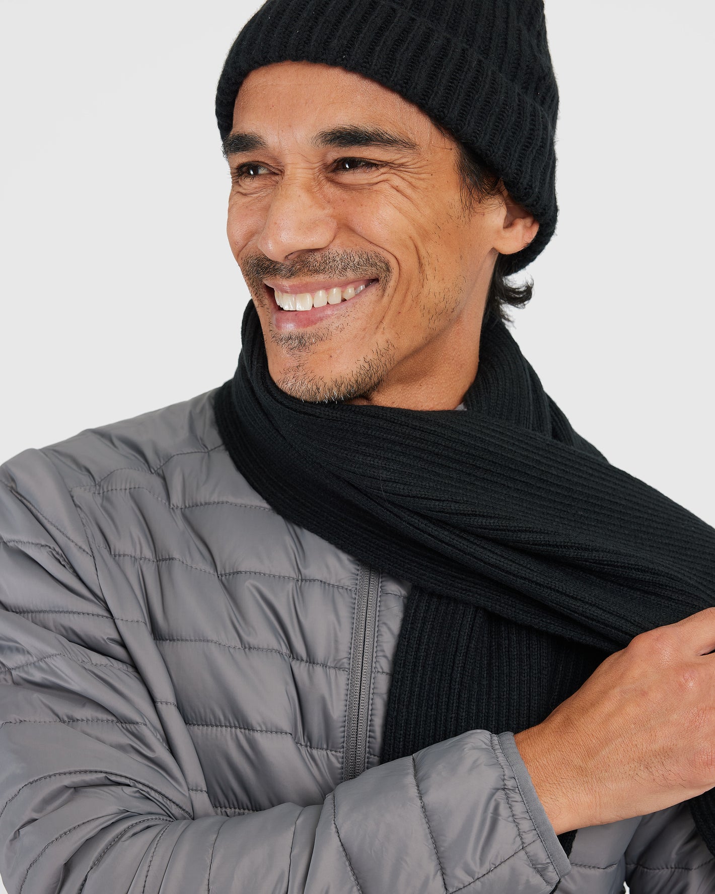 Man smiling in Black Sweater Scarf and quilted jacket.