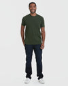 Man in Dark Olive Classic Crew, jeans, and white sneakers, smiling.