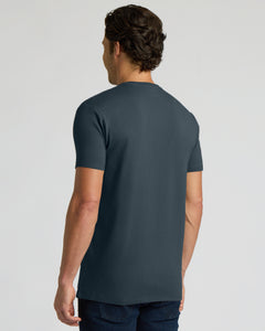 True ClassicA man viewed from the back wearing a dark slate blue crewneck t-shirt and dark jeans, set against a plain light gray studio background.