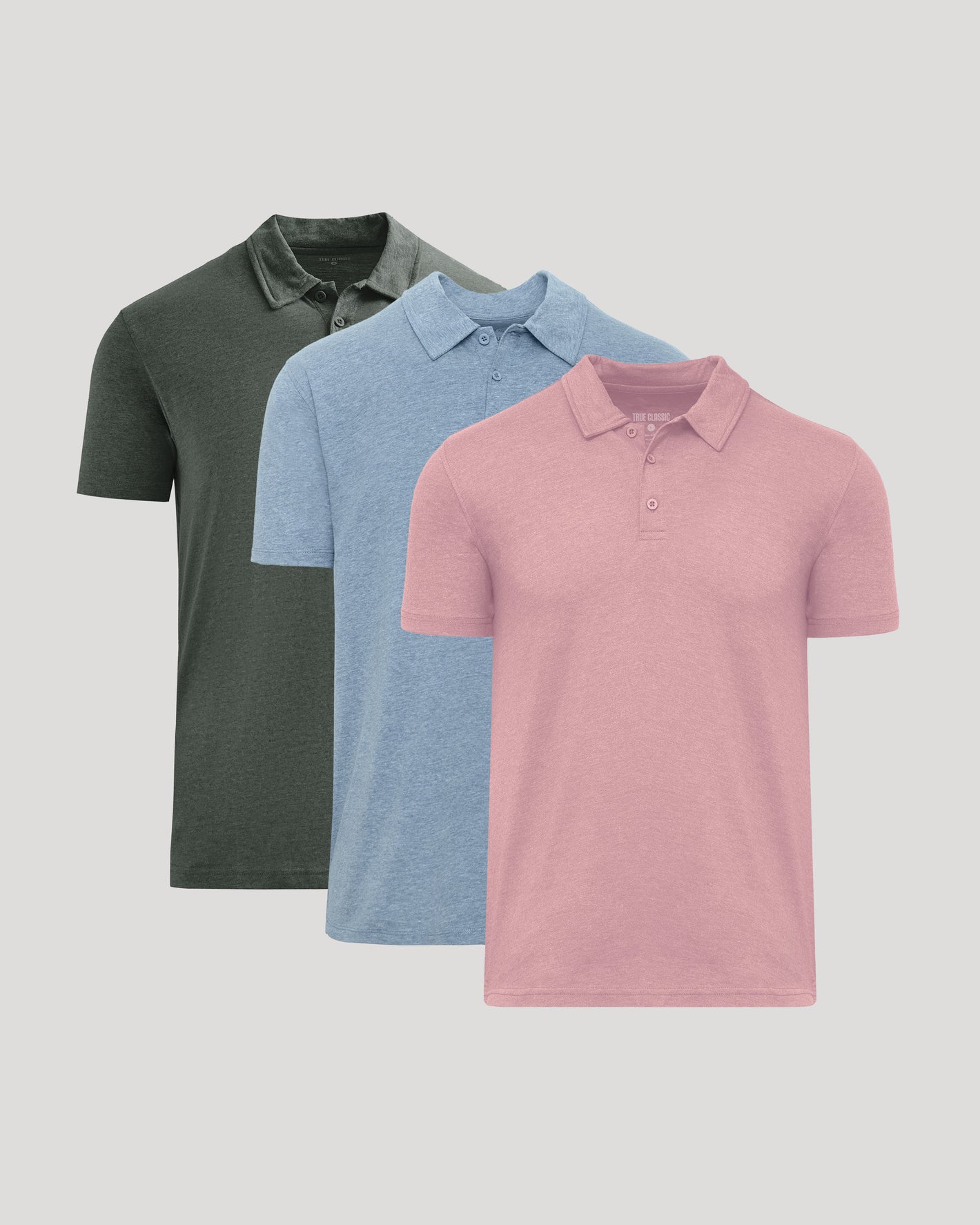 Three short-sleeve polo shirts shown in a layered arrangement on a light gray background: one dark olive green, one light blue, and one pink in front.
