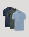 Three short-sleeve polo shirts in navy blue, olive green, and light heather blue, arranged in a staggered overlapping layout on a light gray background.