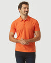 Man wearing Burnt Orange Heather Classic Polo, smiling with hands clasped.