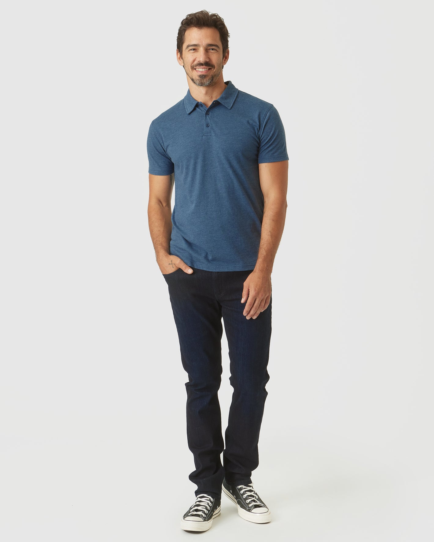 Man wearing Deep Sea Blue Heather Classic Polo, dark jeans, sneakers.