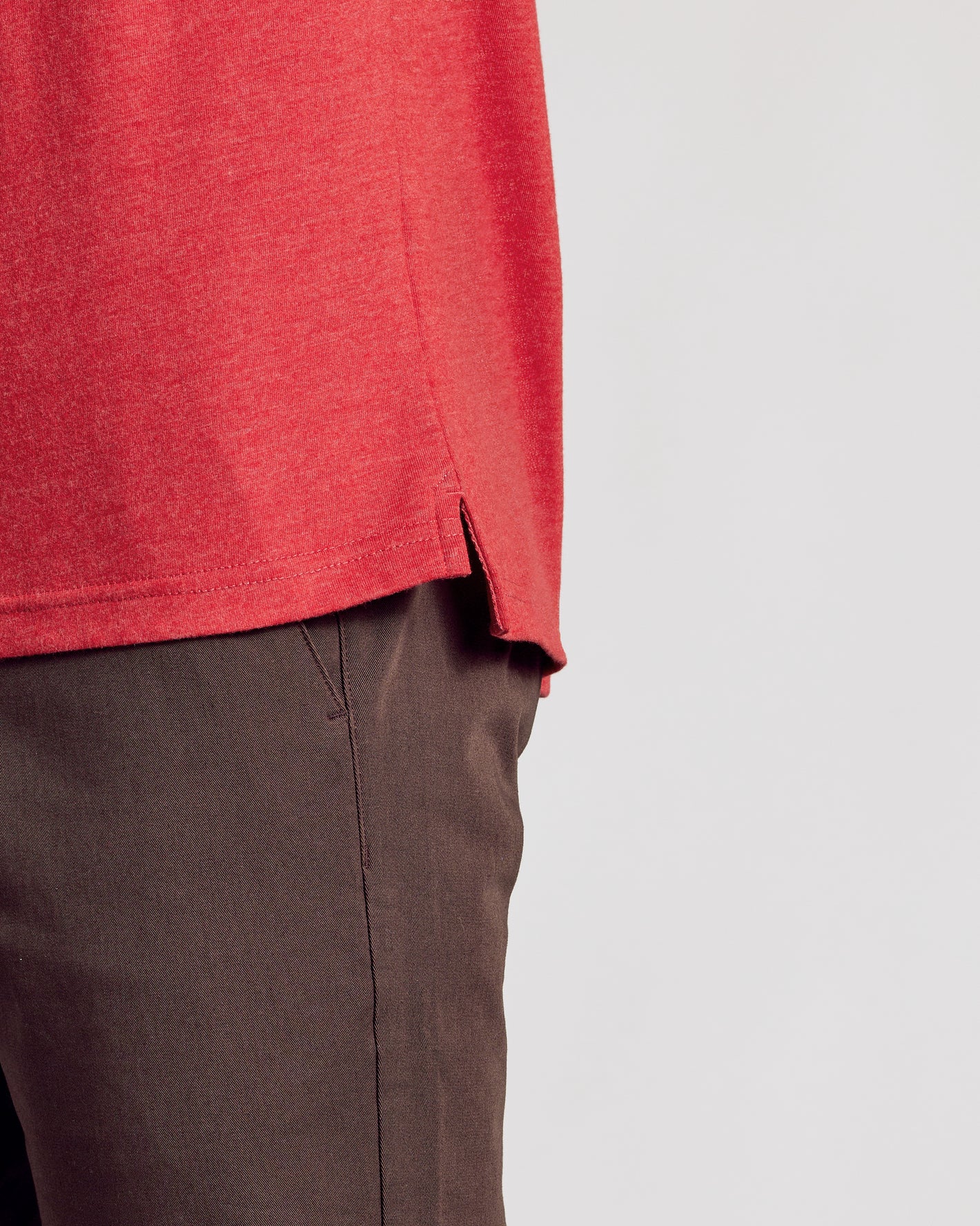 Dark Heather Lava Short Sleeve Polo hem and side slit over brown pants.