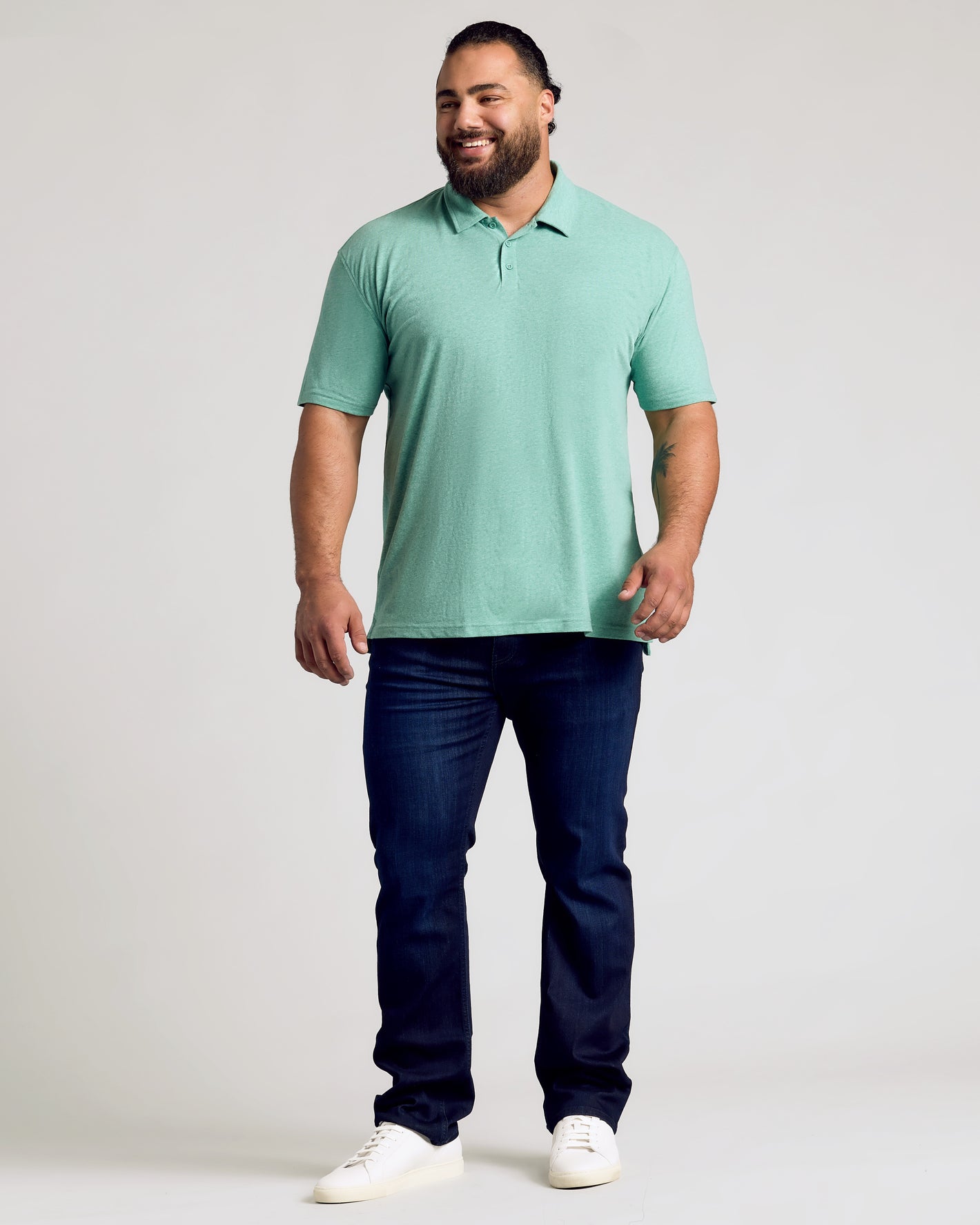 Man wearing Light Heather Greenery Classic Polo, dark jeans, white sneakers.
