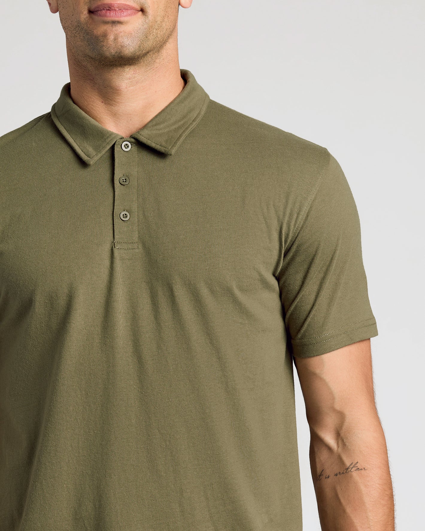 Man wearing olive-green Wardrobe Classic Polo 10-Pack shirt with tattoo visible.