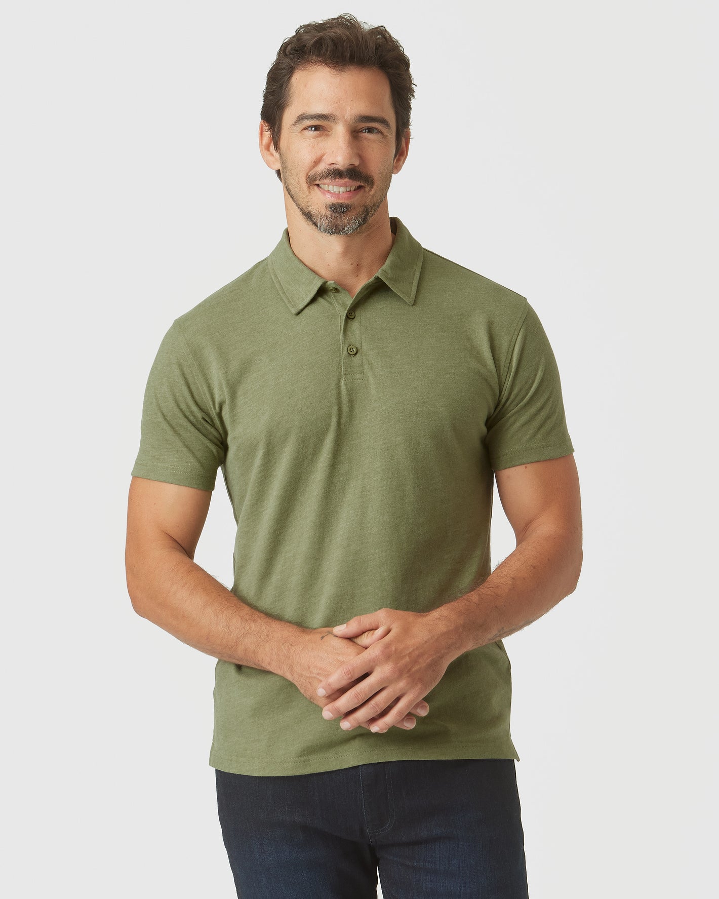 Man in Olive Green Heather Polo, short-sleeve, smiling gently.