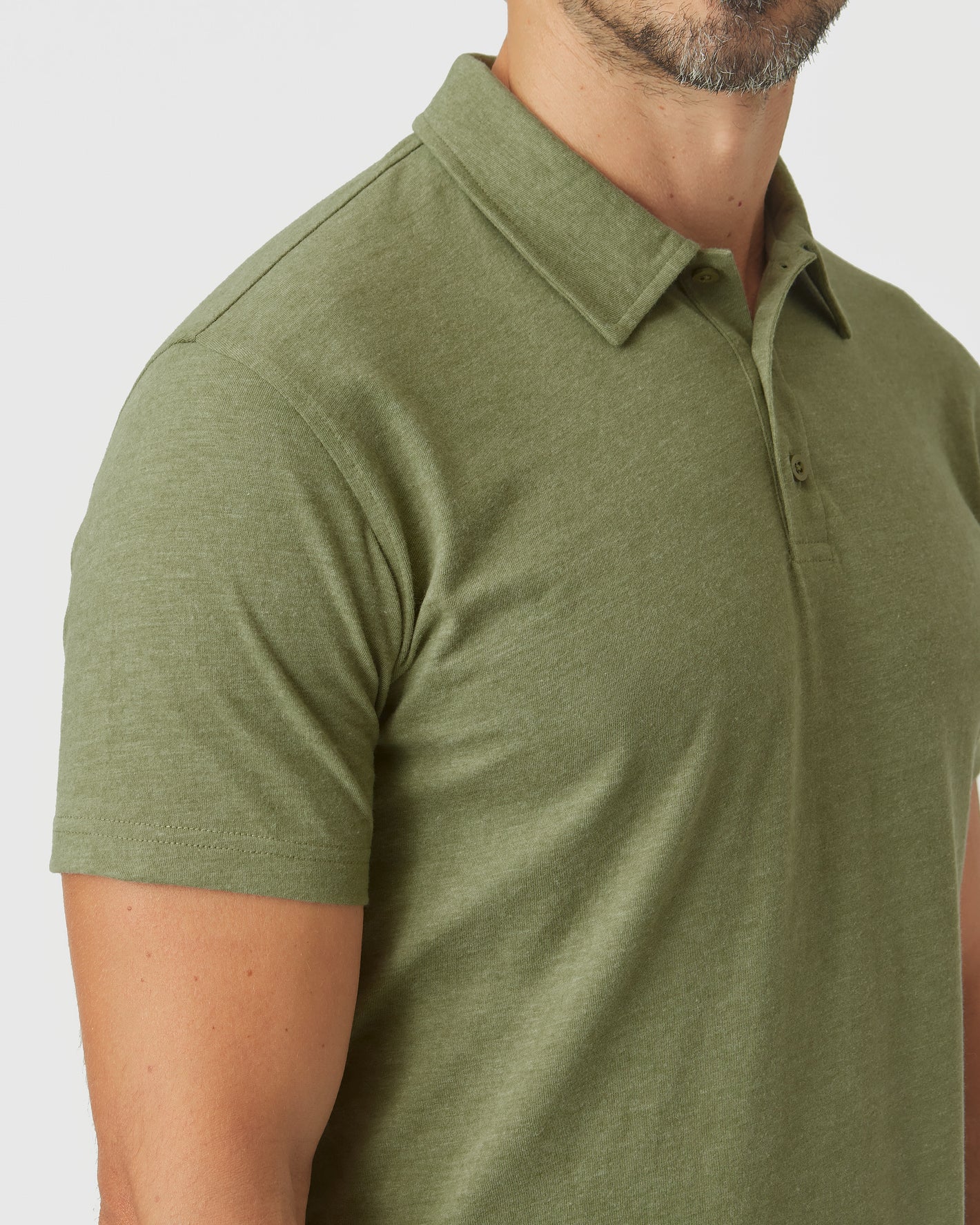 Man wearing Olive Green Heather Polo, showcasing its short sleeves and fitted design.