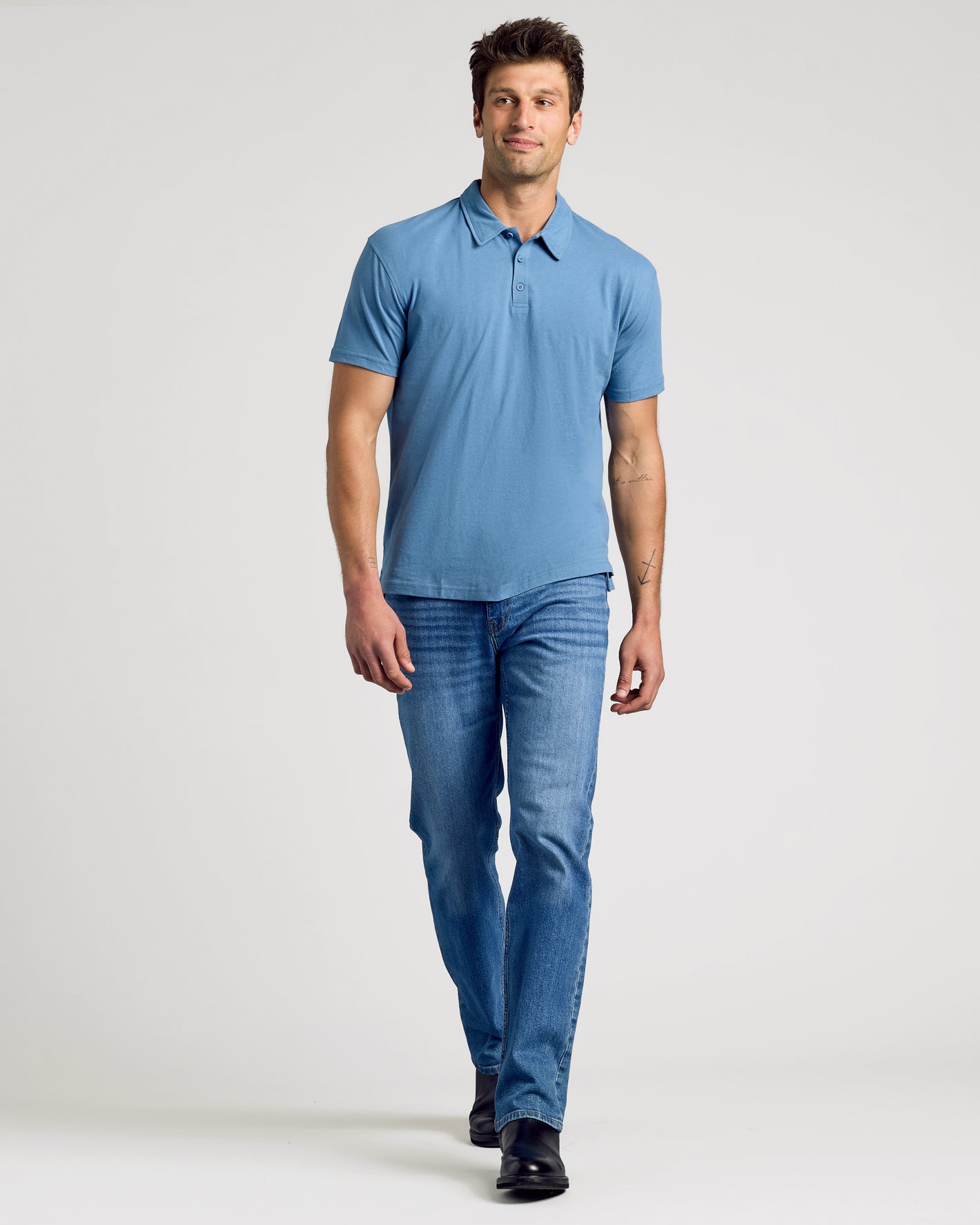 Man wearing a blue polo shirt and jeans on a white background