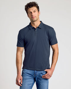 True ClassicMan wearing a navy blue polo shirt and jeans on a light gray background