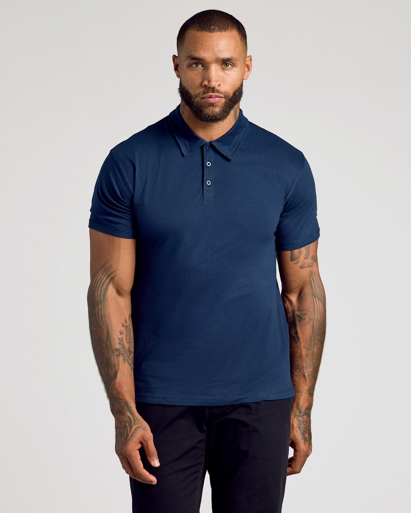 Man wearing a navy blue polo shirt against a plain background