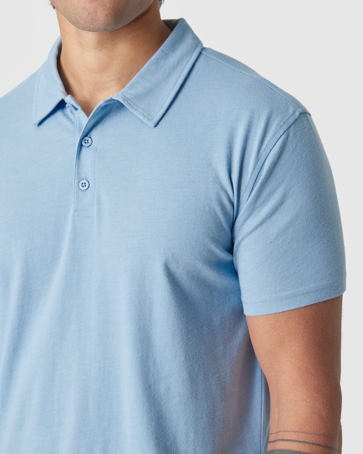 Sky Blue Heather Polo with classic collar and two buttons, worn by model.