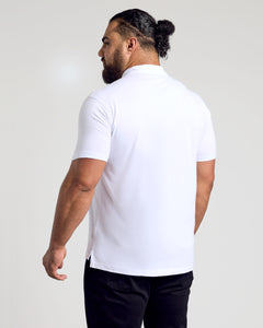 True ClassicMan in White Classic Polo, dark trousers, hair in bun, facing away.