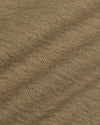 A close-up of a woven fabric texture in a warm taupe-brown color, showing the detailed knit pattern and subtle diagonal folds.