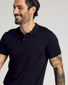 Smiling man wearing Black Short Sleeve Sweater Polo, showcasing tattoos.