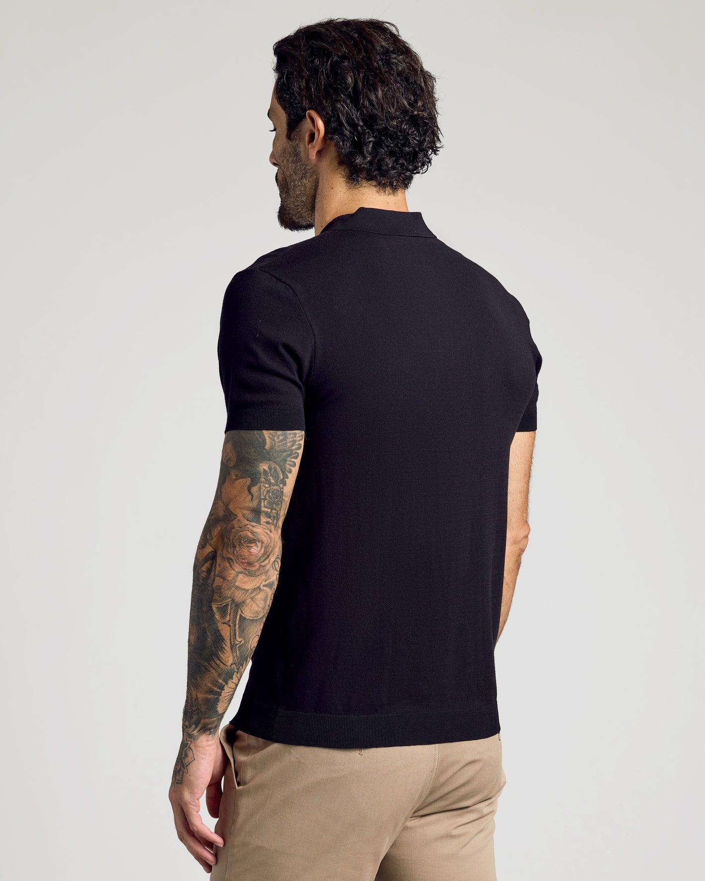 Man wearing a Black Short Sleeve Sweater Polo, showcasing tattoos.