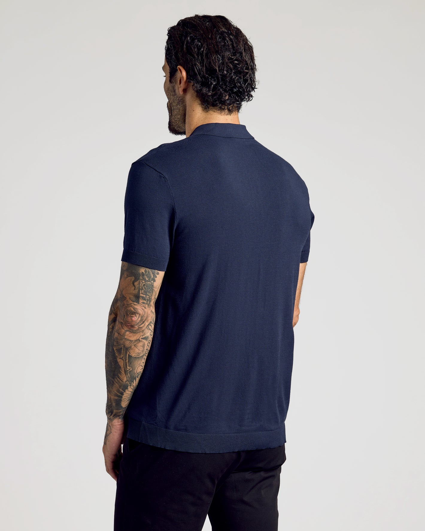 Man in Navy Short Sleeve Sweater Polo with tattooed arm.