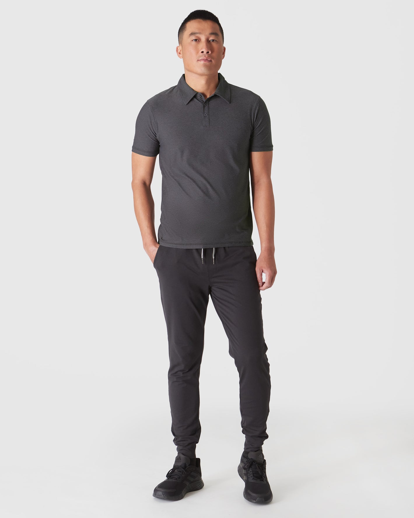 Man wearing Dark Heather Tempest Active Polo 2.0 with black joggers.