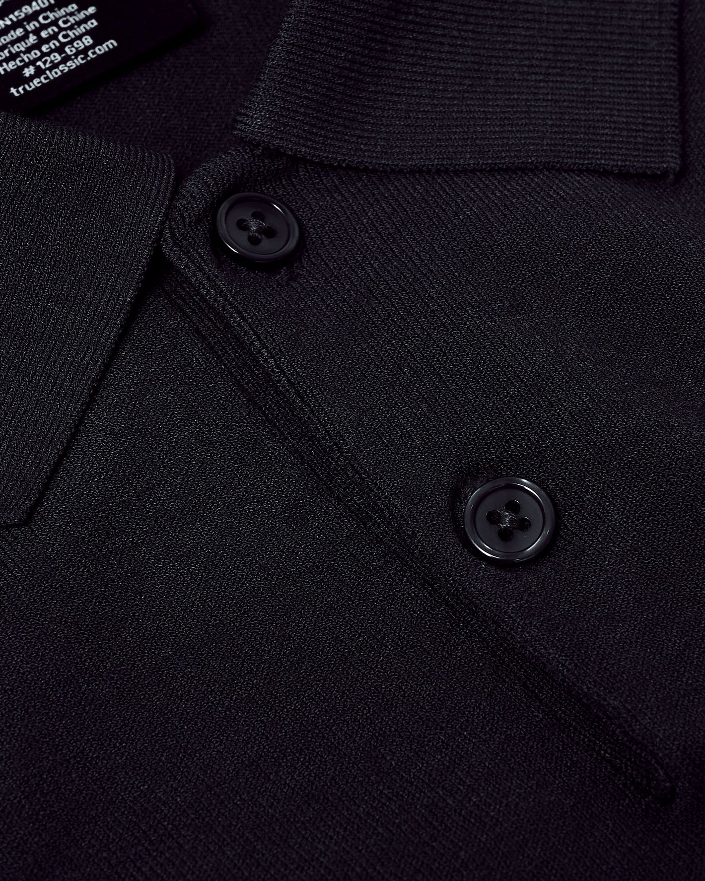 Black Dressy Polo close-up showing textured fabric, collar, and buttons.