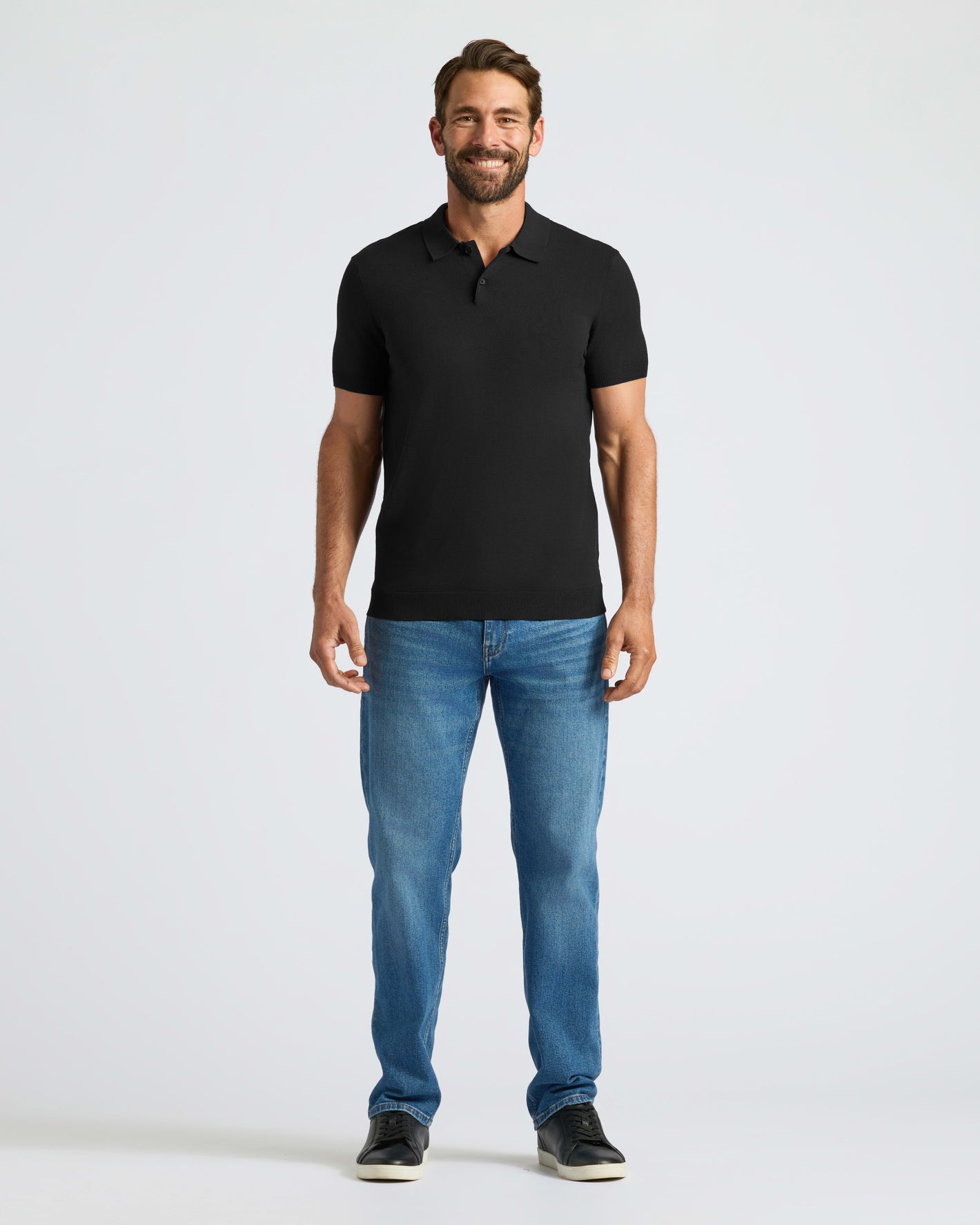 Man wearing Black Dressy Polo, blue jeans, and black sneakers.