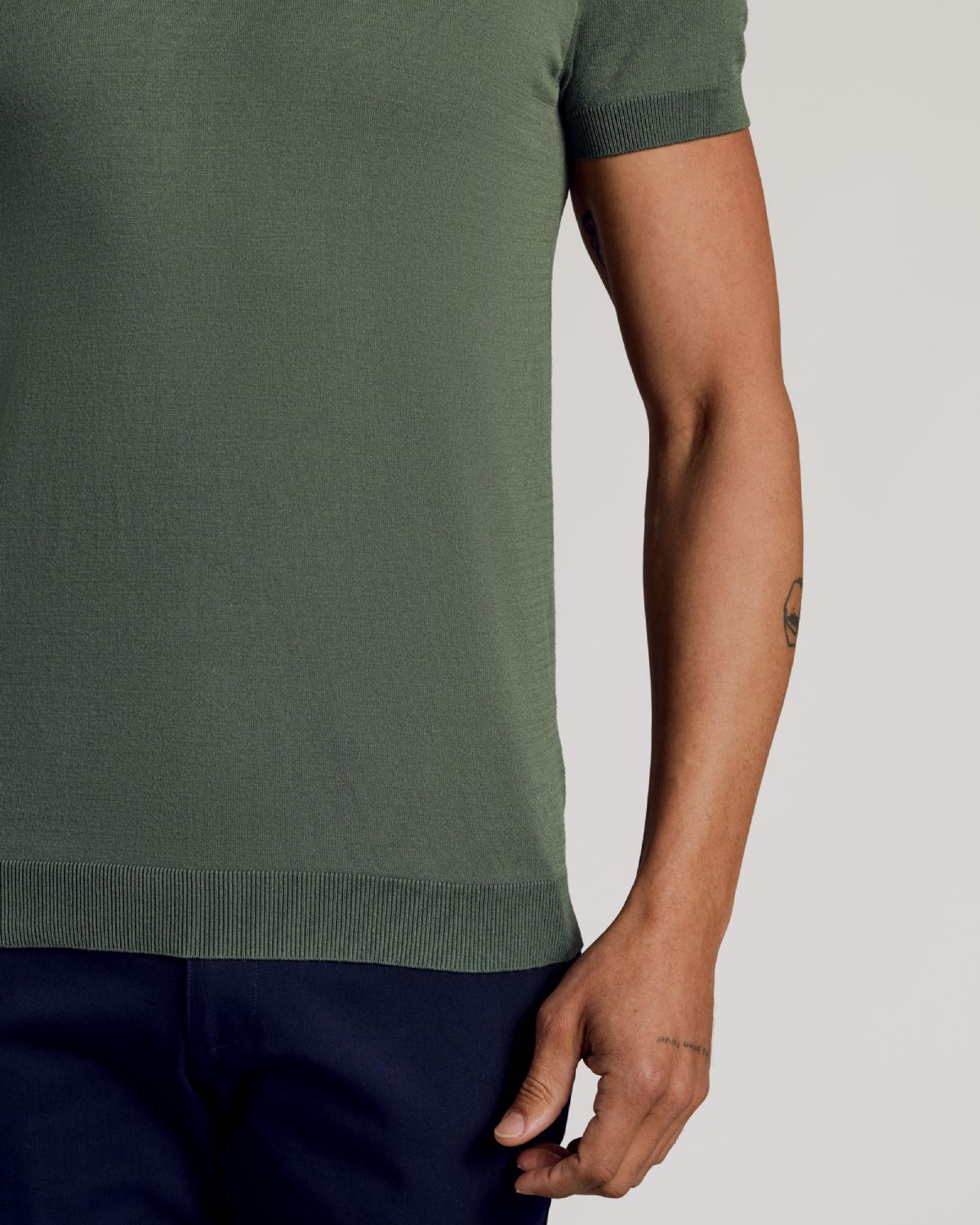 Moss Dressy Polo on a person, showing fit and forearm tattoos.