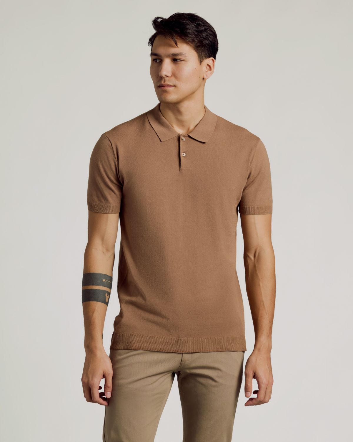 Young man wearing Truffle Dressy Polo with relaxed pose, showing tattoo.