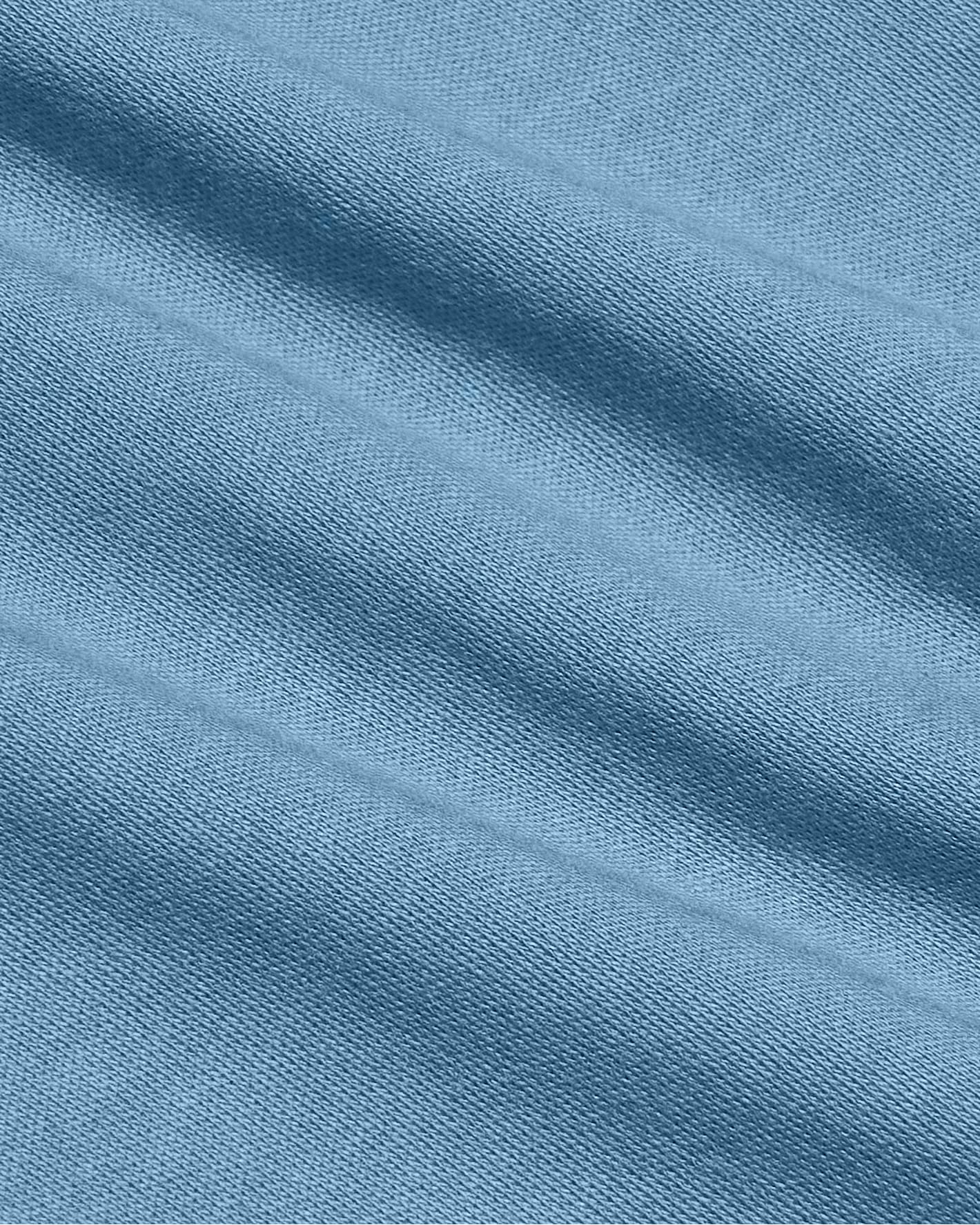 A close-up of a light blue knit fabric with soft diagonal folds and a fine ribbed texture.