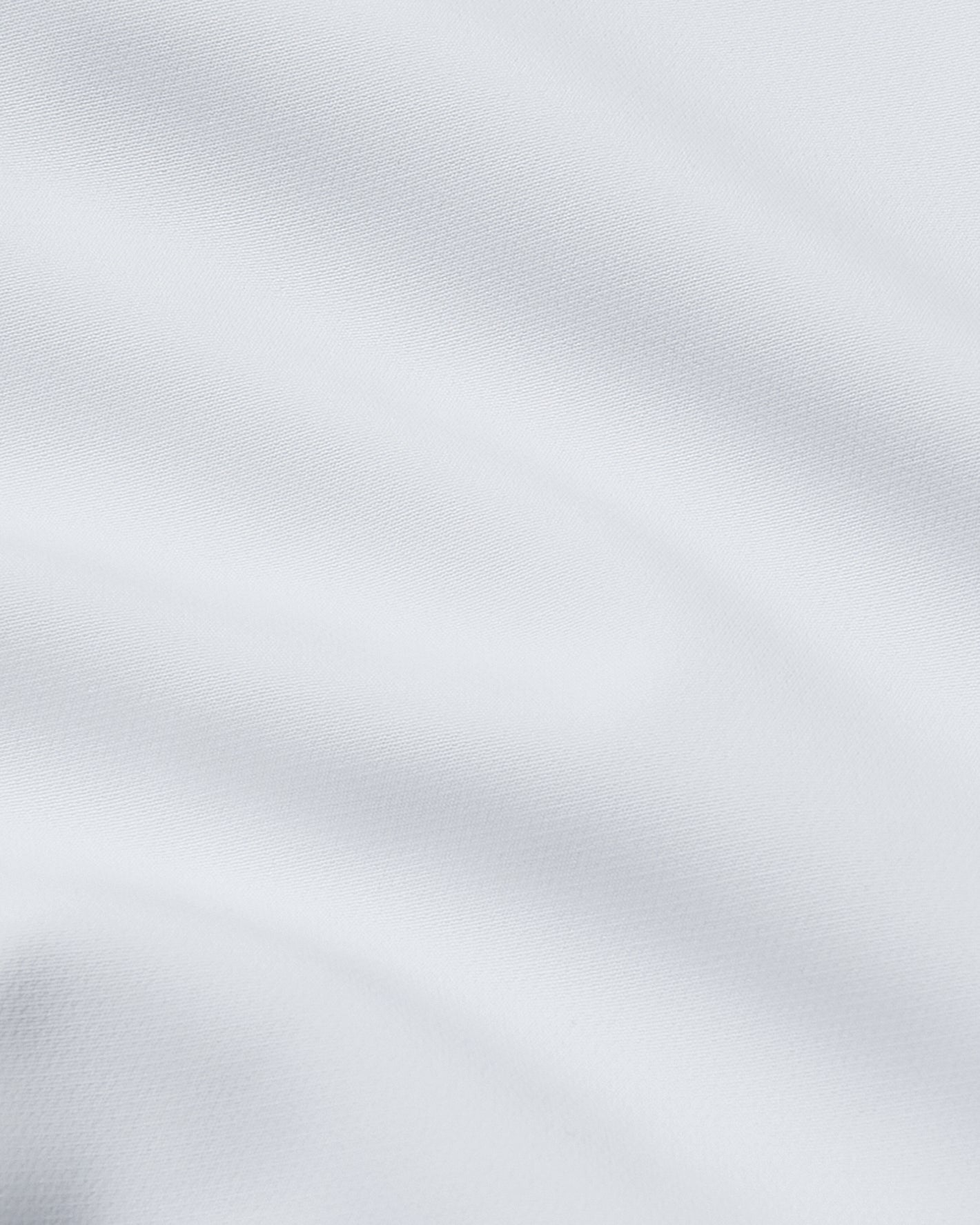 White Performance Dress Shirt with subtle weave and gentle fabric folds.