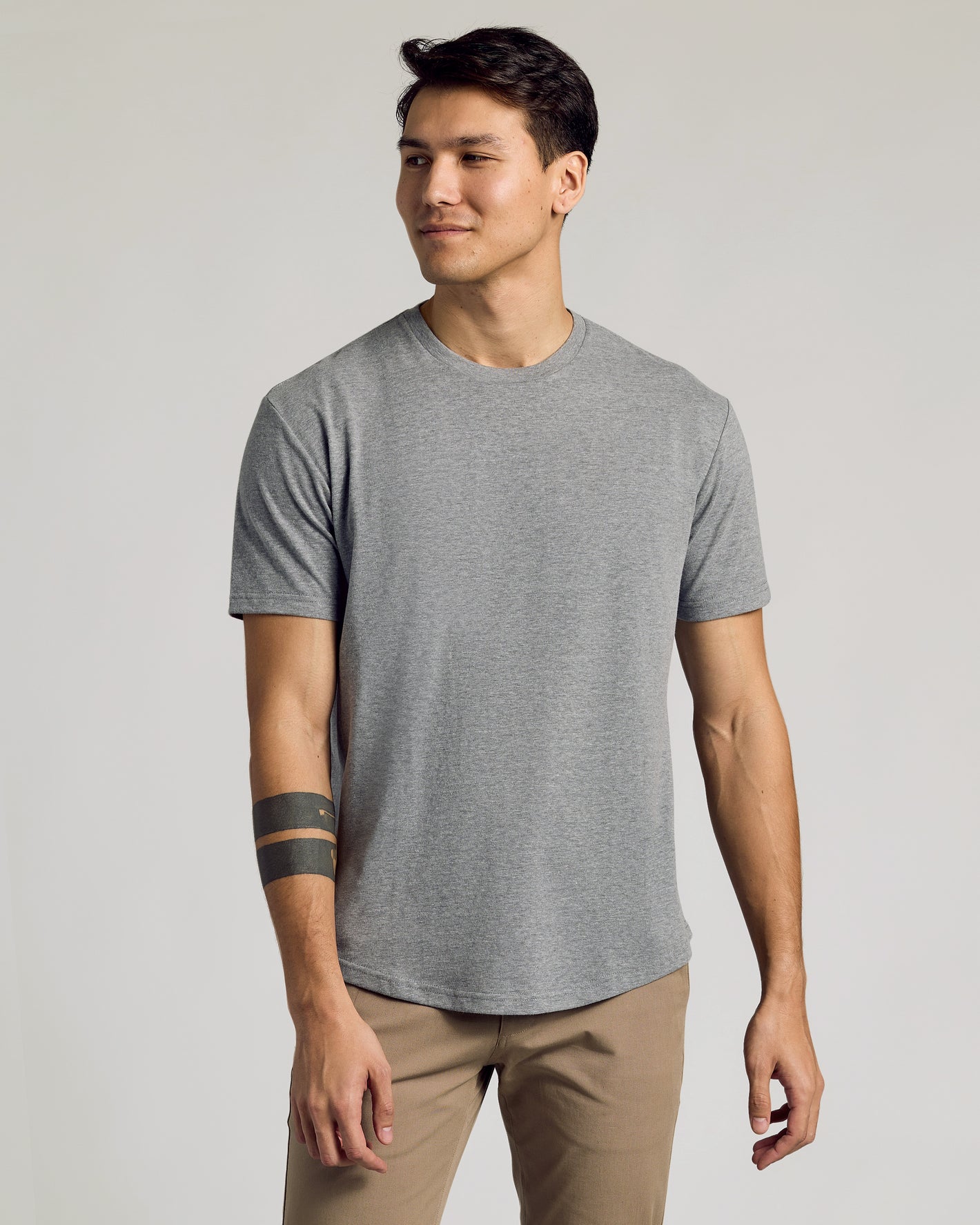The Staple Curved Hem Classic Crew Neck in heather-gray worn by a man.