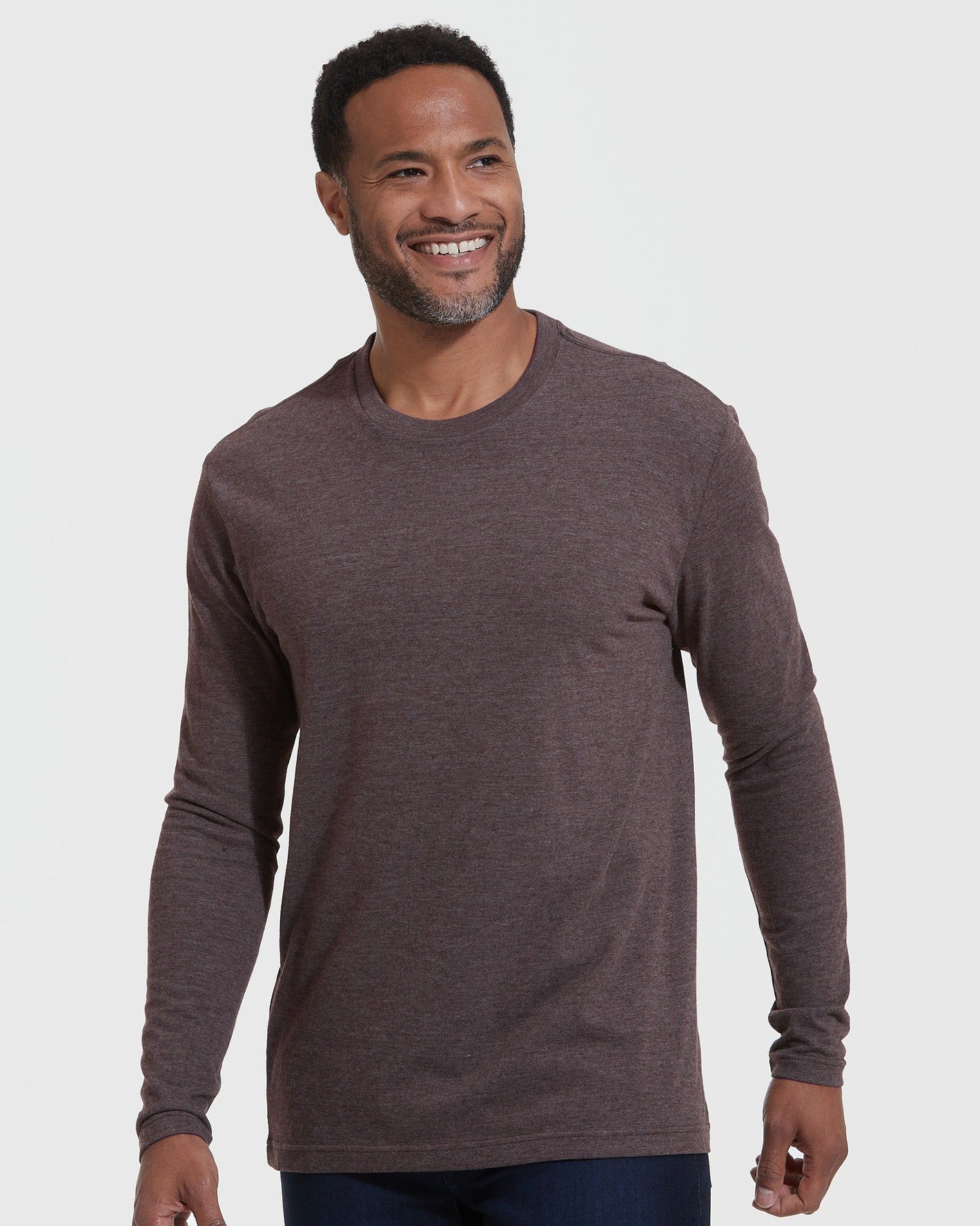 Man wearing Heather Dark Oak Classic Long Sleeve Crew Neck, smiling slightly off-camera.