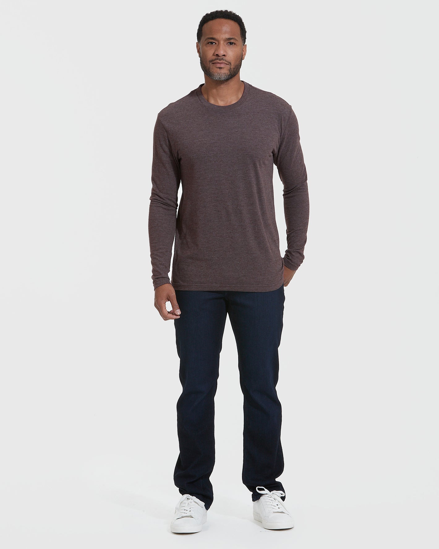 Man wearing Heather Dark Oak Classic Long Sleeve Crew Neck, dark jeans, white sneakers.
