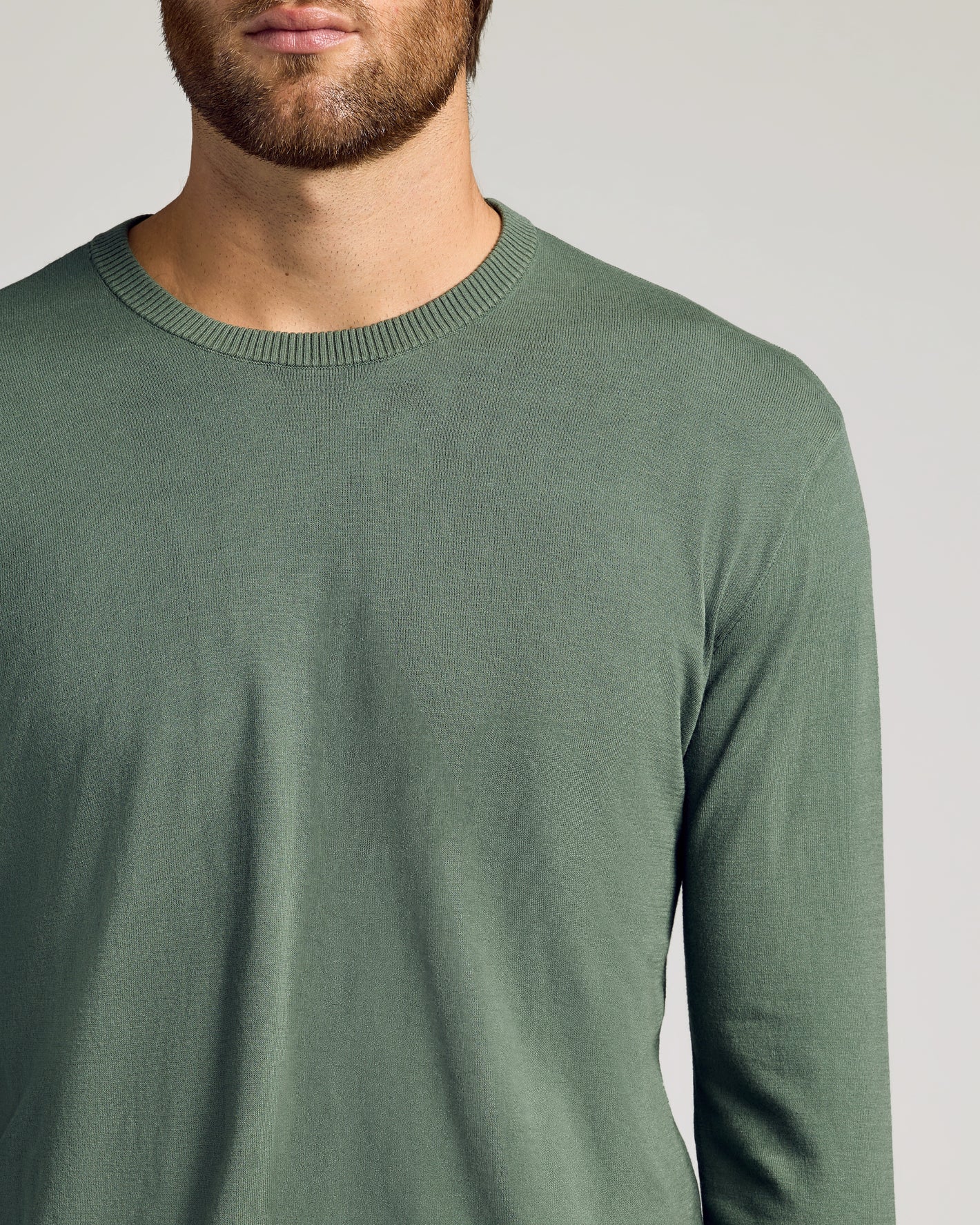 Man wearing Black & Moss Crew Neck Sweater, slim fit, long-sleeved, muted green.