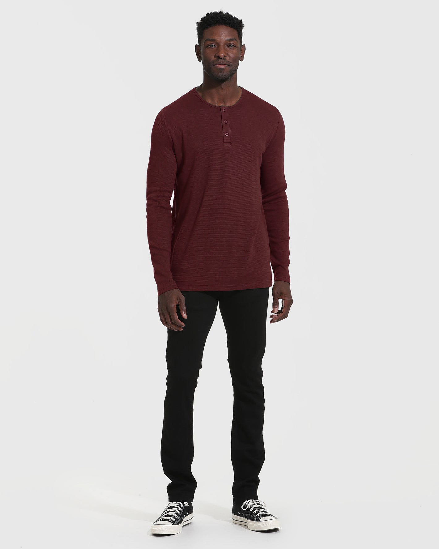 Man wearing Mahogany Long Sleeve Waffle Henley with slim-fit black pants.
