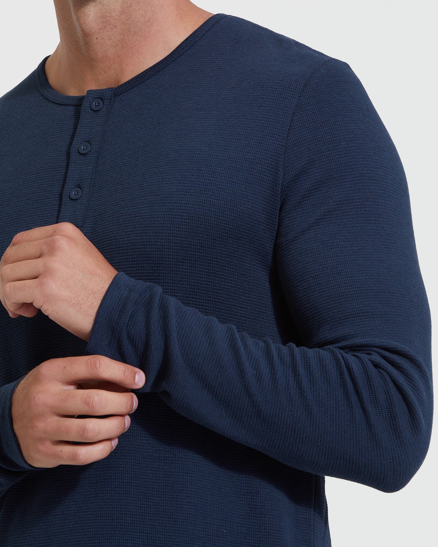 Man wearing Navy Waffle Long Sleeve Henley, adjusting sleeve, highlighting texture.