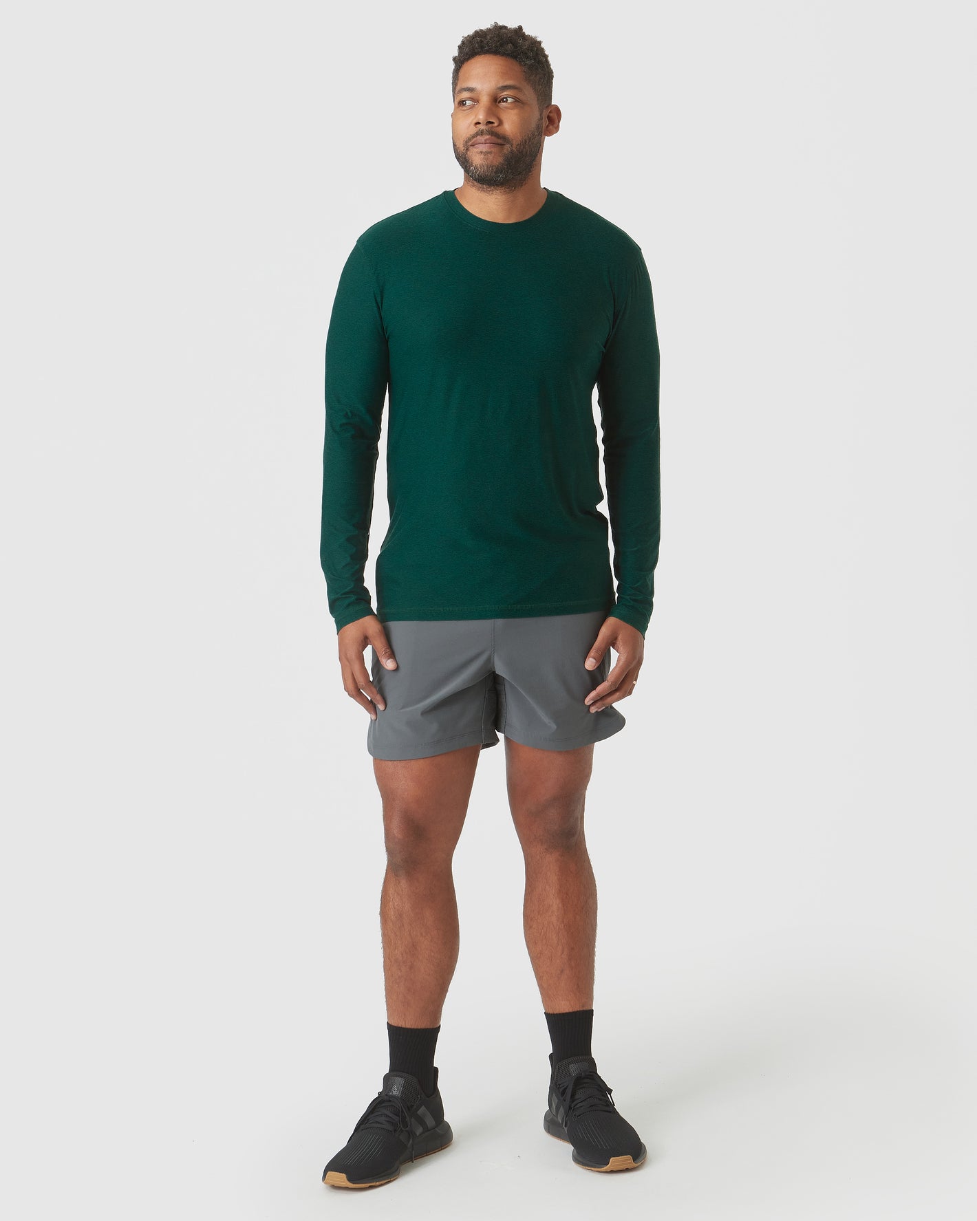 Man wearing Evergreen Heather Active Long Sleeve Crew T-Shirt with athletic shorts.
