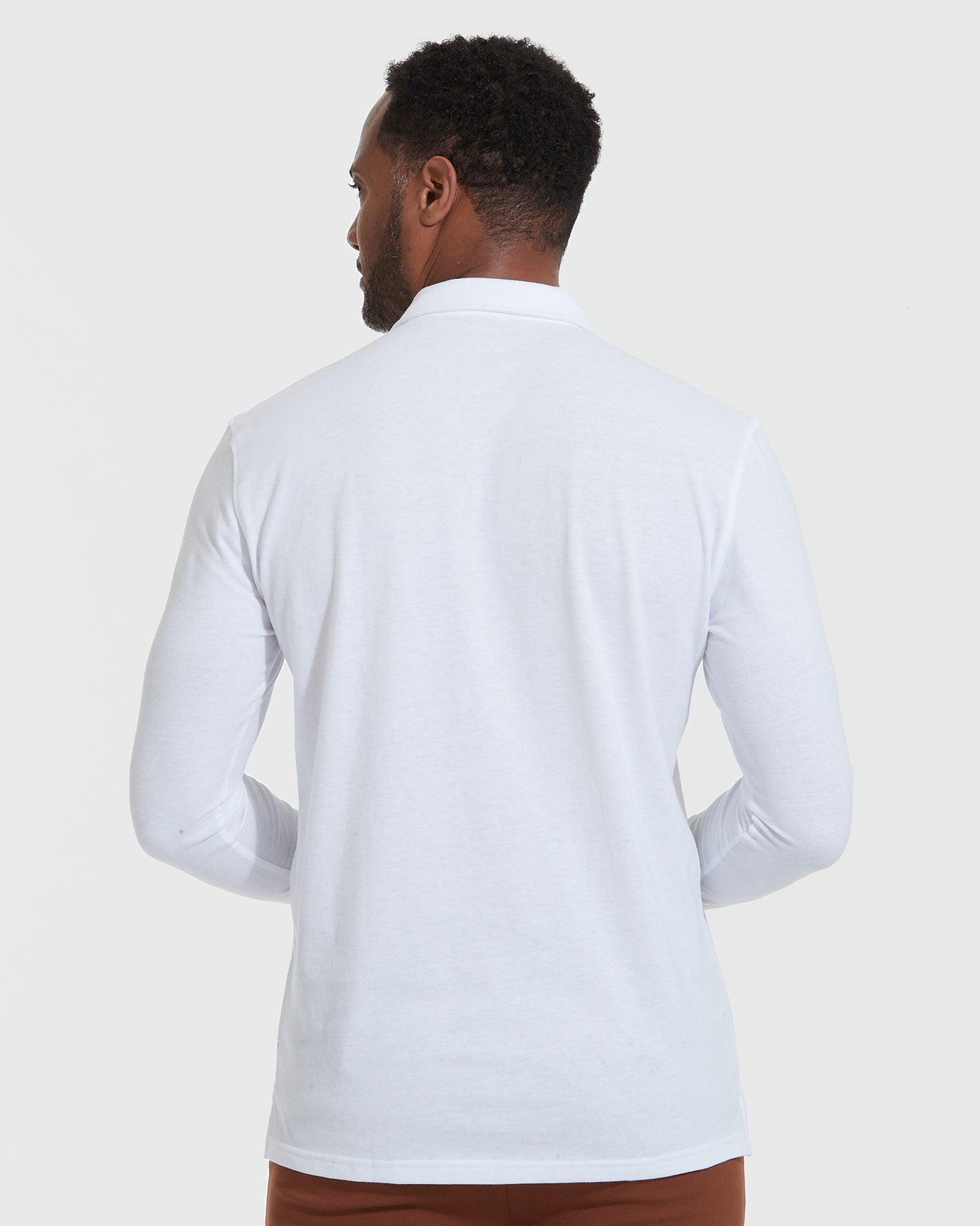 White Long Sleeve Polo worn by man from back view.