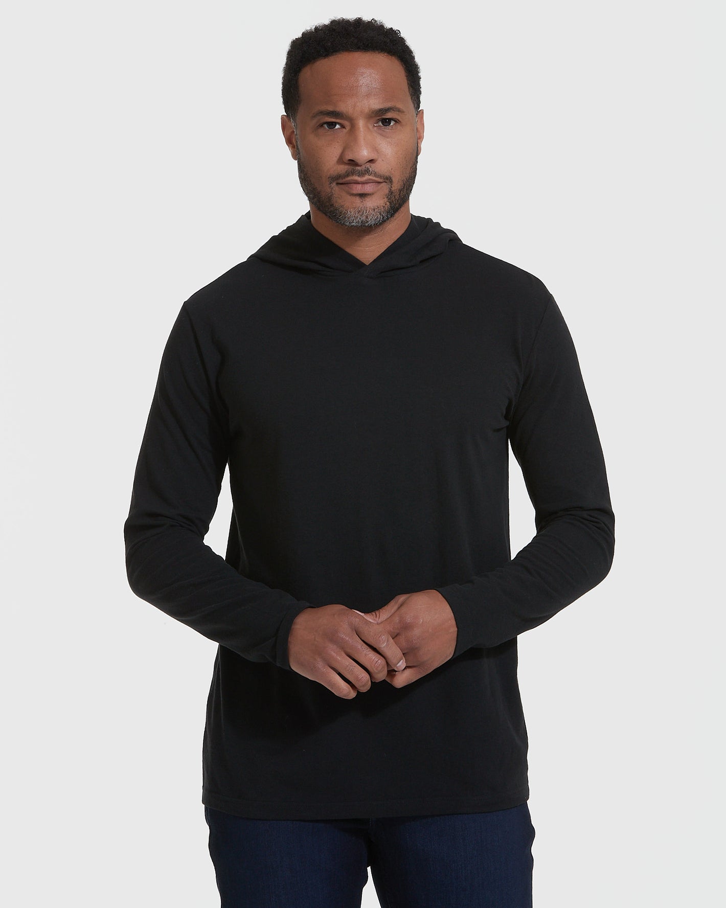 Black Hooded Long Sleeve T-Shirt worn by man against plain background.