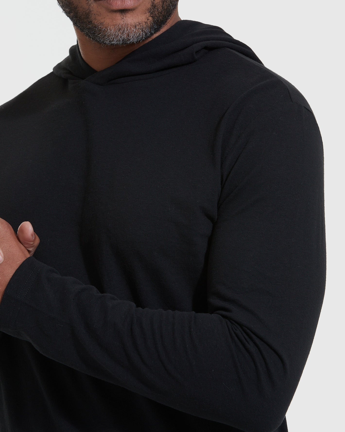 Black Hooded Long Sleeve T-Shirt on a person with clasped hands.