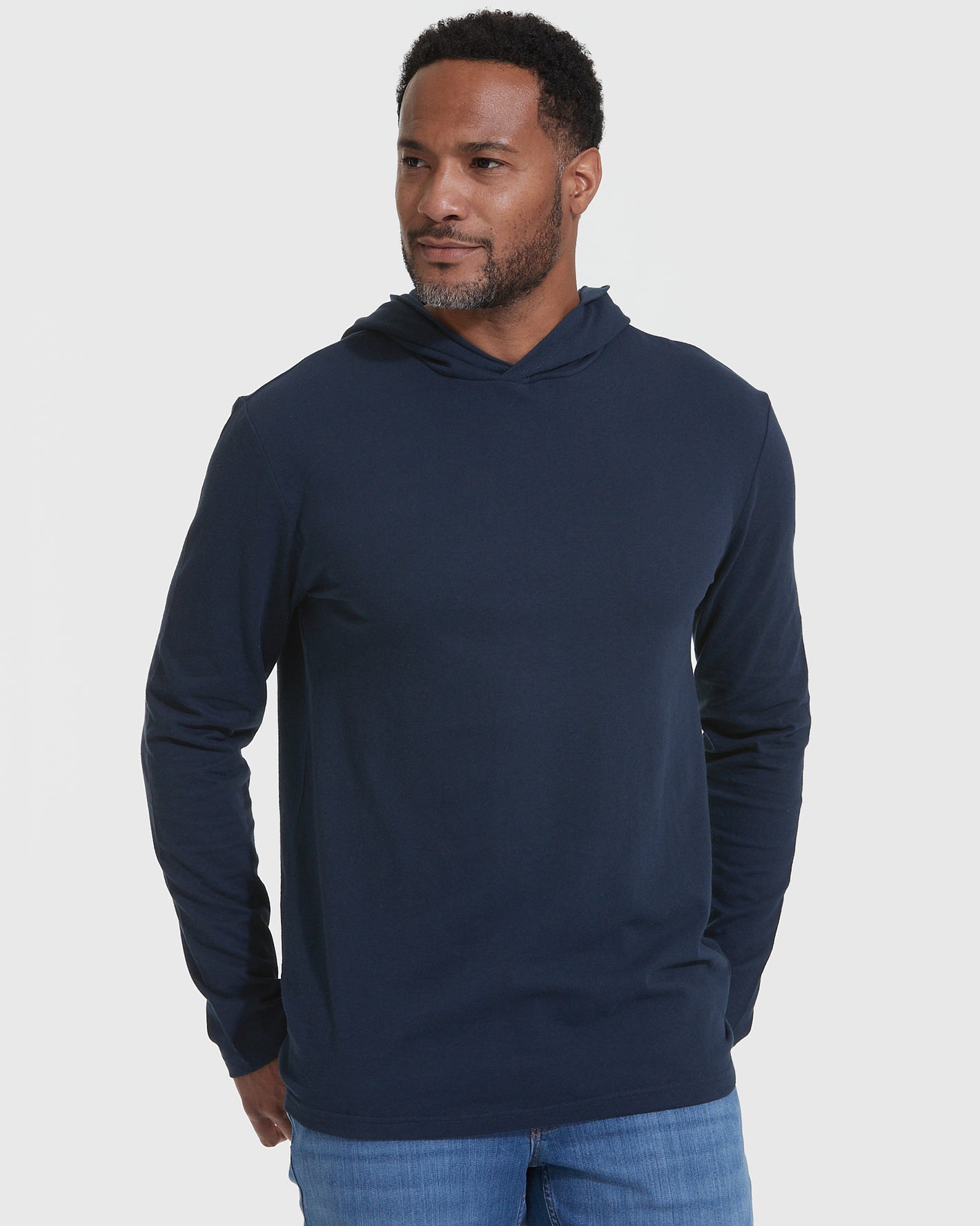 Man in Navy Hooded Long Sleeve T-Shirt against gray background.