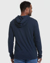 Man wearing Navy Hooded Long Sleeve T-Shirt, jeans, light background.