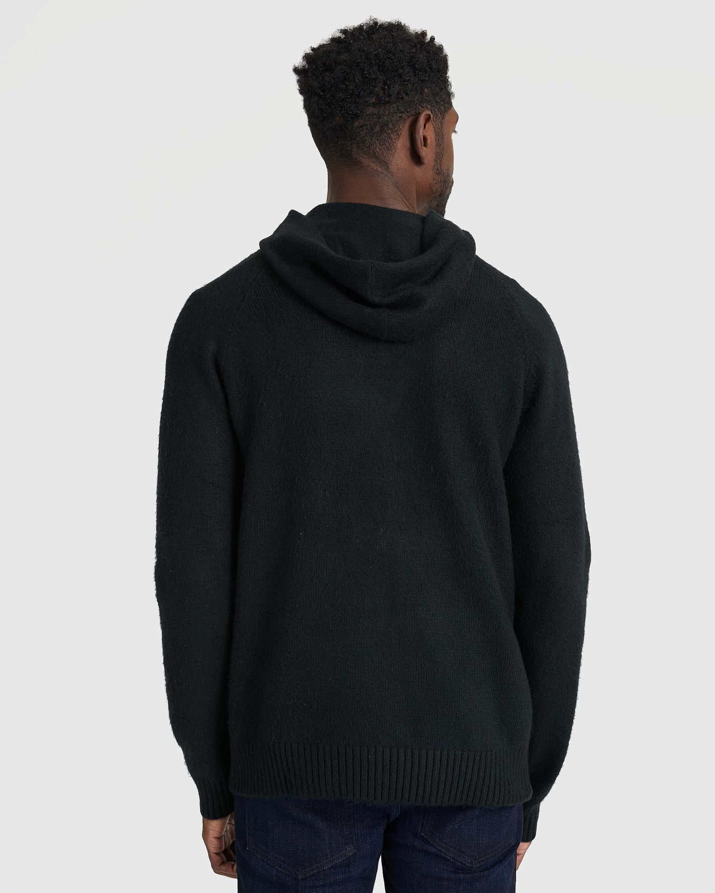 Black Sweater Hoodie with ribbed cuffs, hem, and hood worn with jeans.