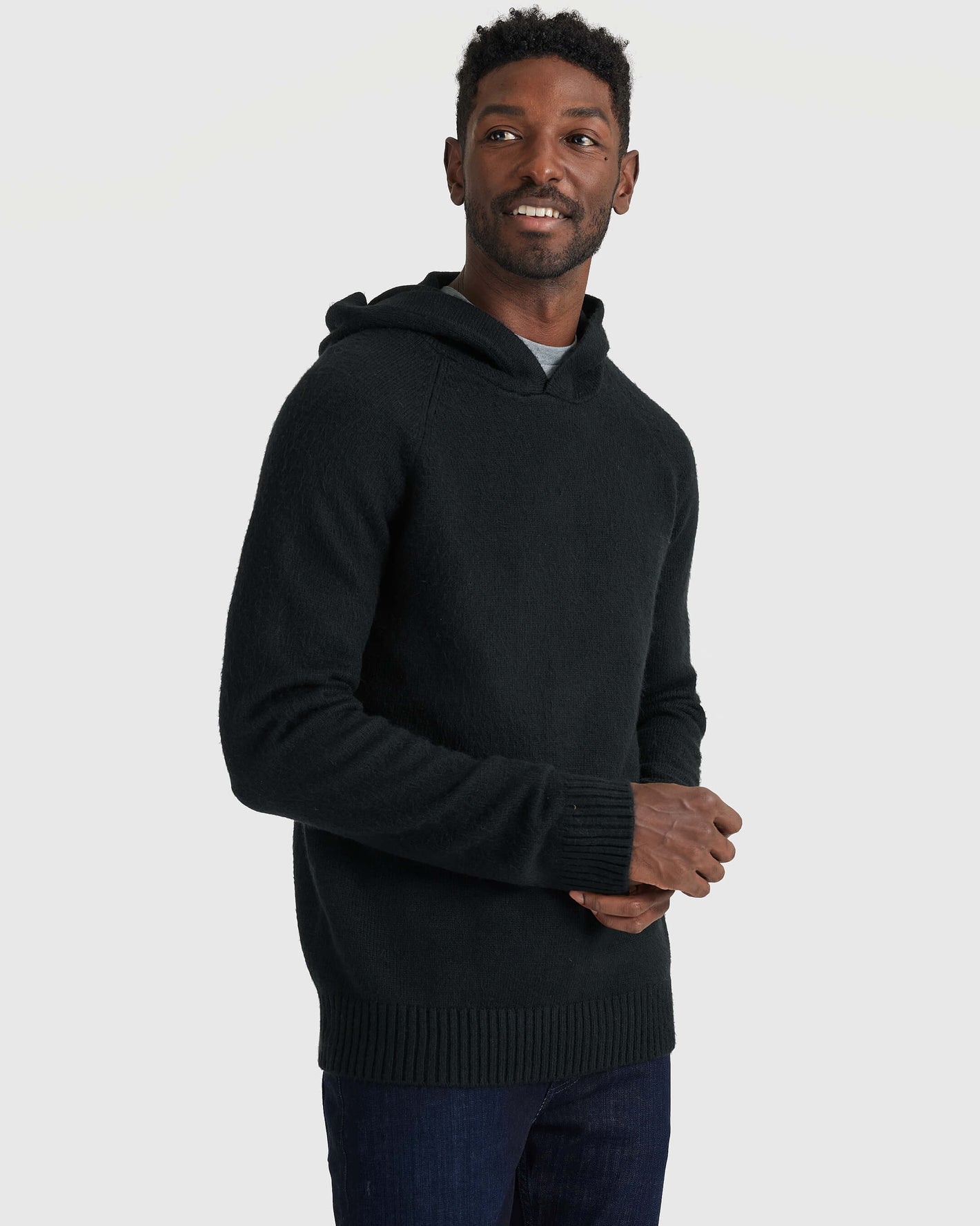 Man wearing Black Sweater Hoodie, layered over T-shirt, with jeans.