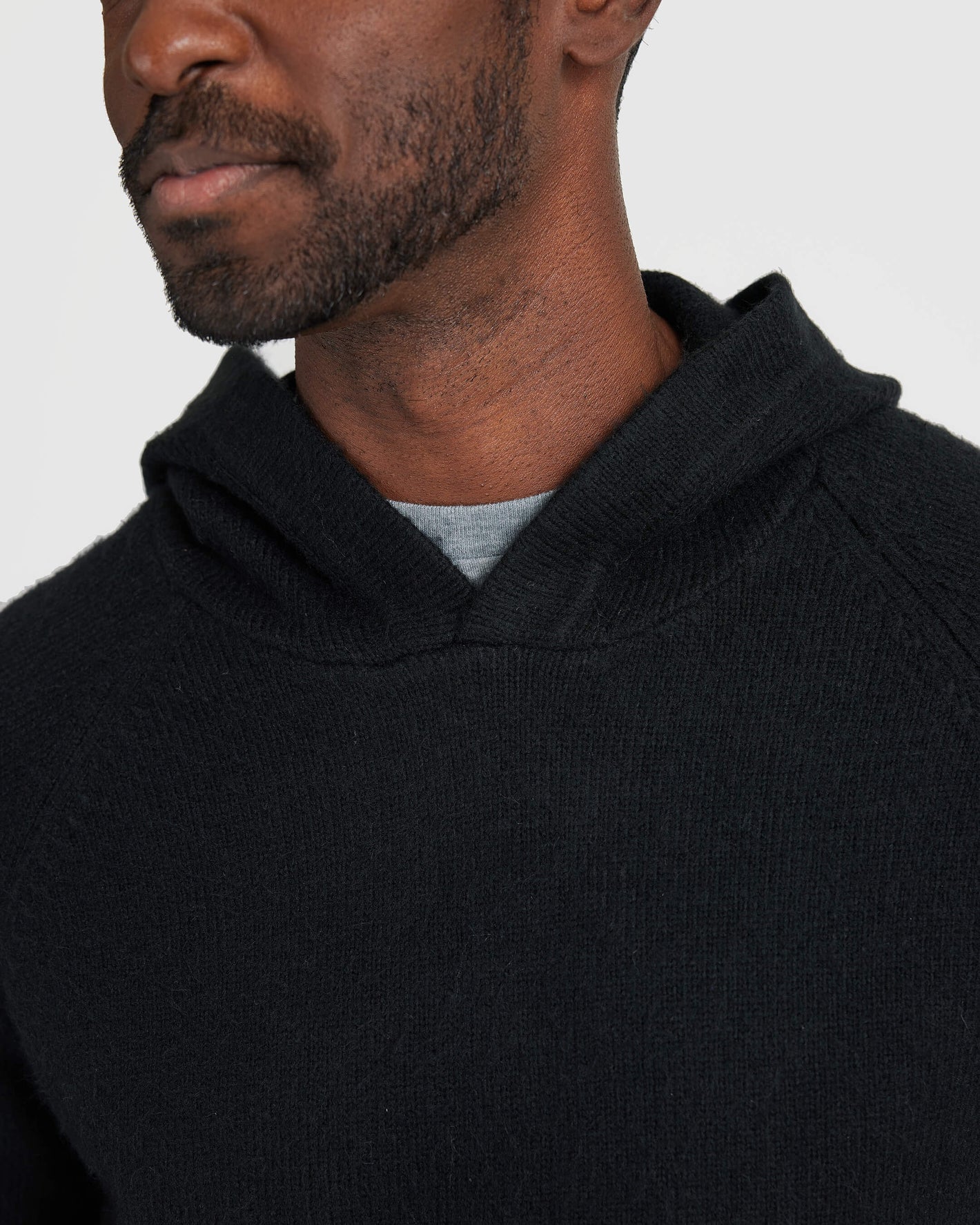 Man wearing Black Sweater Hoodie with beard, light gray shirt visible.