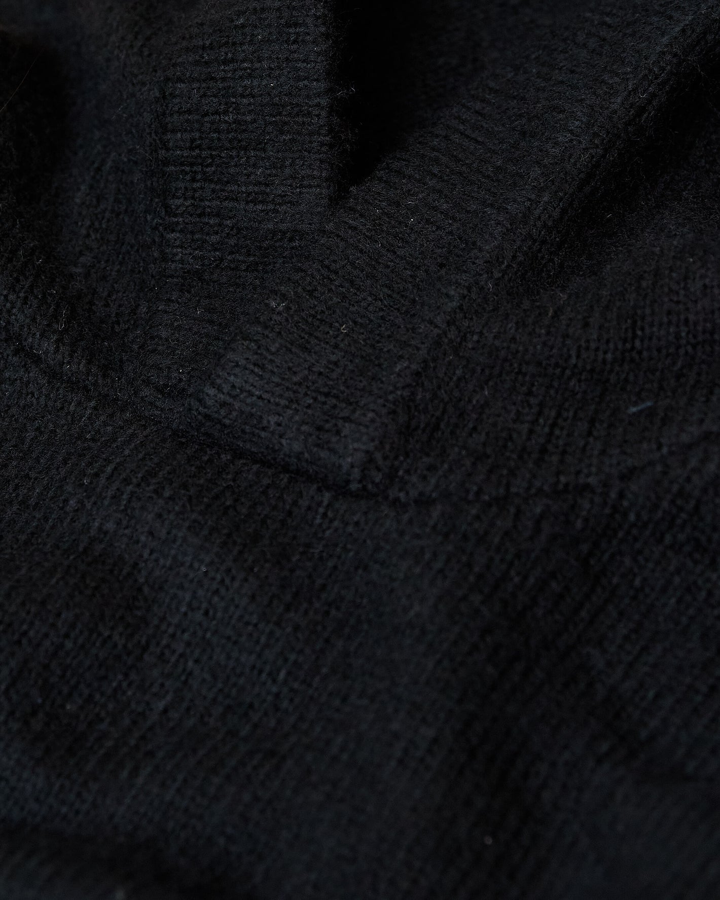 Black Sweater Hoodie showcasing ribbed texture and fabric folds.