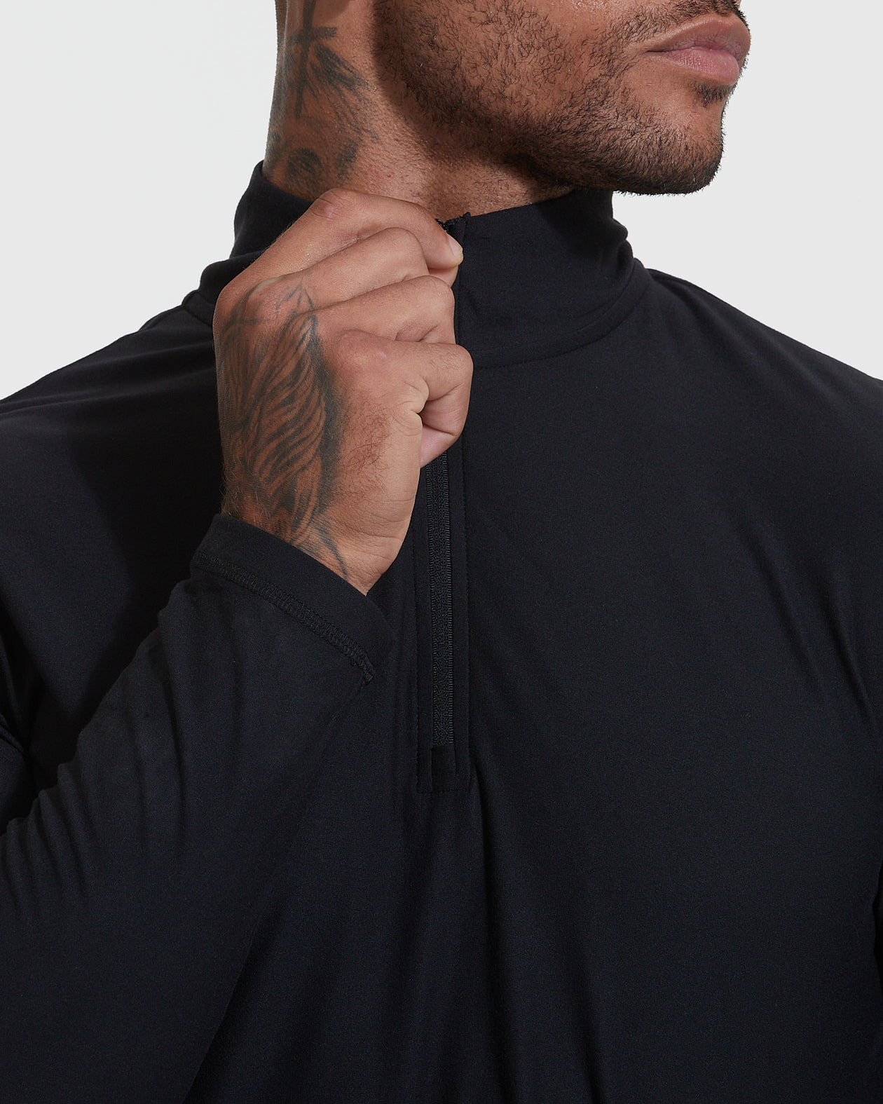 Black Active Quarter Zip Shirt showcasing hand on zipper, tattooed neck.